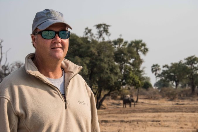 Charlie on the walking safari with an elephant behind him